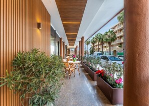 Un couloir aux murs lambrés, avec des sièges à l’extérieur et des plantes en pot.