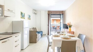 A compact kitchen with modern appliances, a dining area with a table set for four, and a sofa in the background. - Charming and Comfy Apartment in Alghero (Alghero)