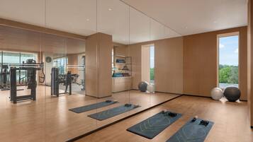 A gym with exercise equipment, yoga mats, and large exercise balls.