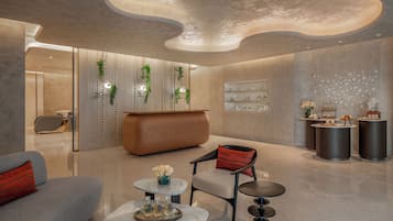 Un hall d’entrée moderne avec un comptoir d’accueil incurvé, un espace salon et des panneaux muraux décoratifs.