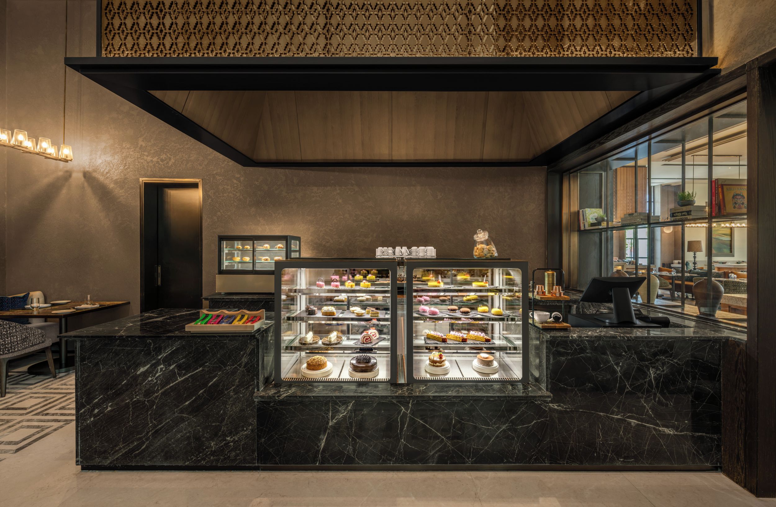 A modern interior with a marble counter displaying pastries and a coffee machine.