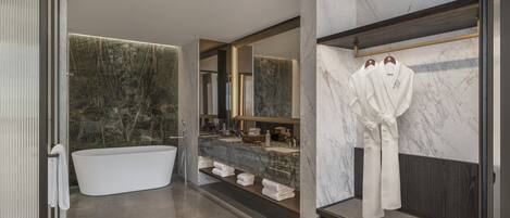 Une salle de bain moderne avec une baignoire sur pieds, des murs en marbre et un meuble-lavabo avec un miroir.