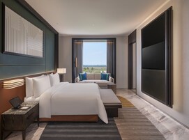 Une chambre d’hôtel avec un grand lit, un canapé, une télévision et une vue sur l’extérieur.
