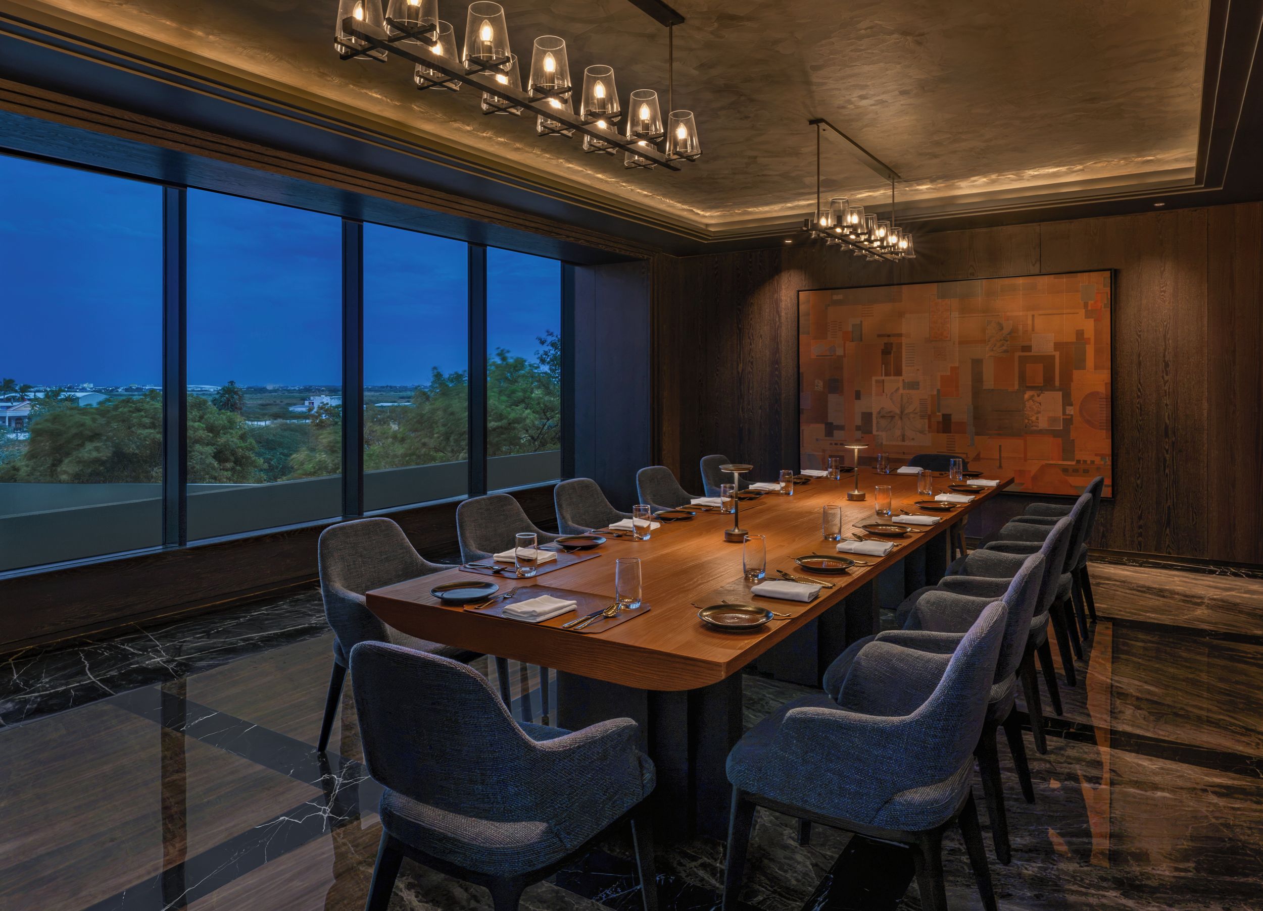 Un salón de conferencias con una larga mesa, sillas y vistas al exterior.
