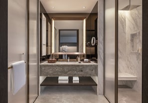 Un baño moderno con un espejo grande, encimera de mármol y un perchero.