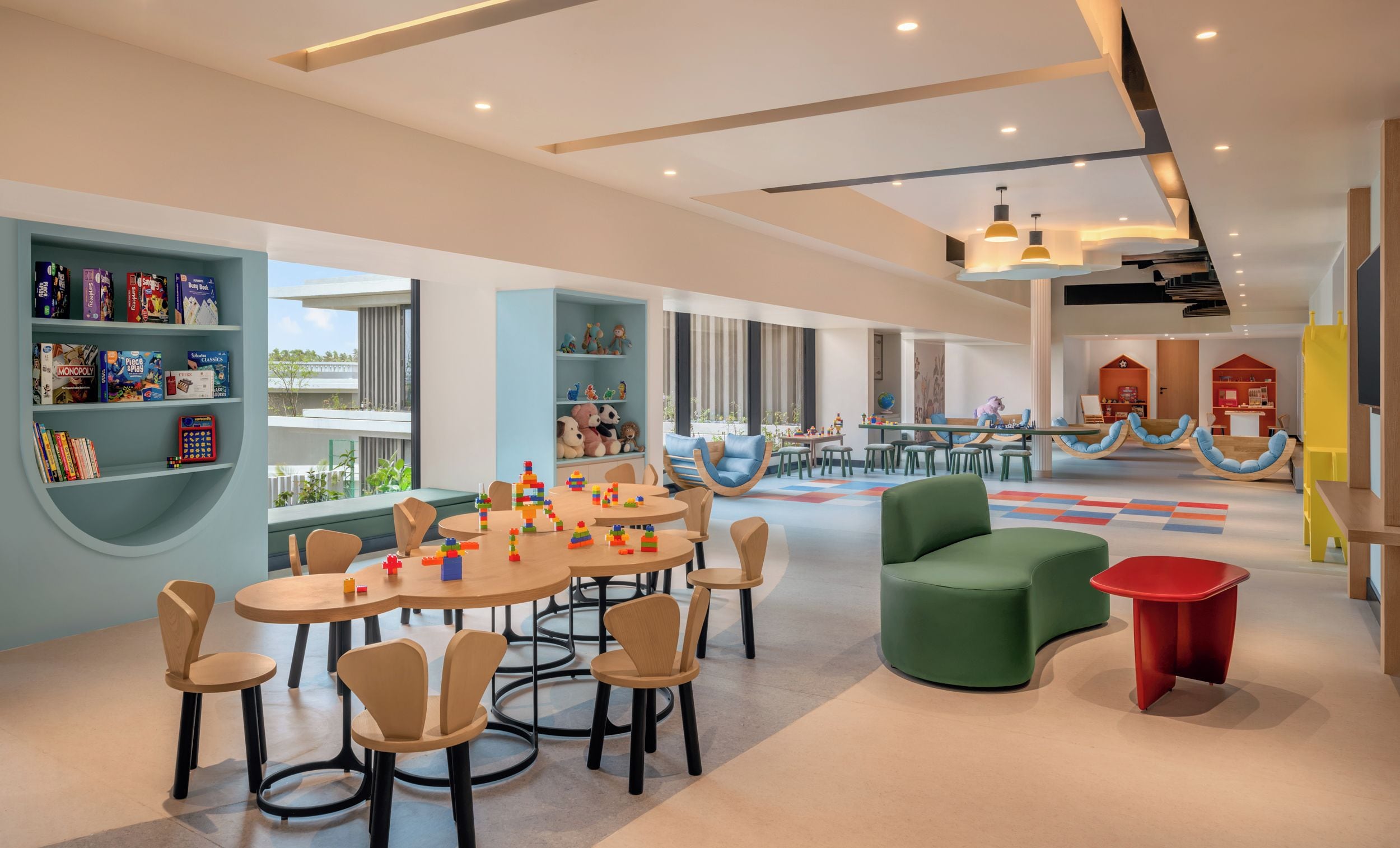 Un espace de jeux pour enfants avec des tables, des chaises et des jouets colorés.