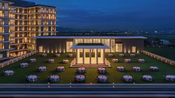 A multi-story hotel with a rooftop dining area featuring round tables and chairs.
