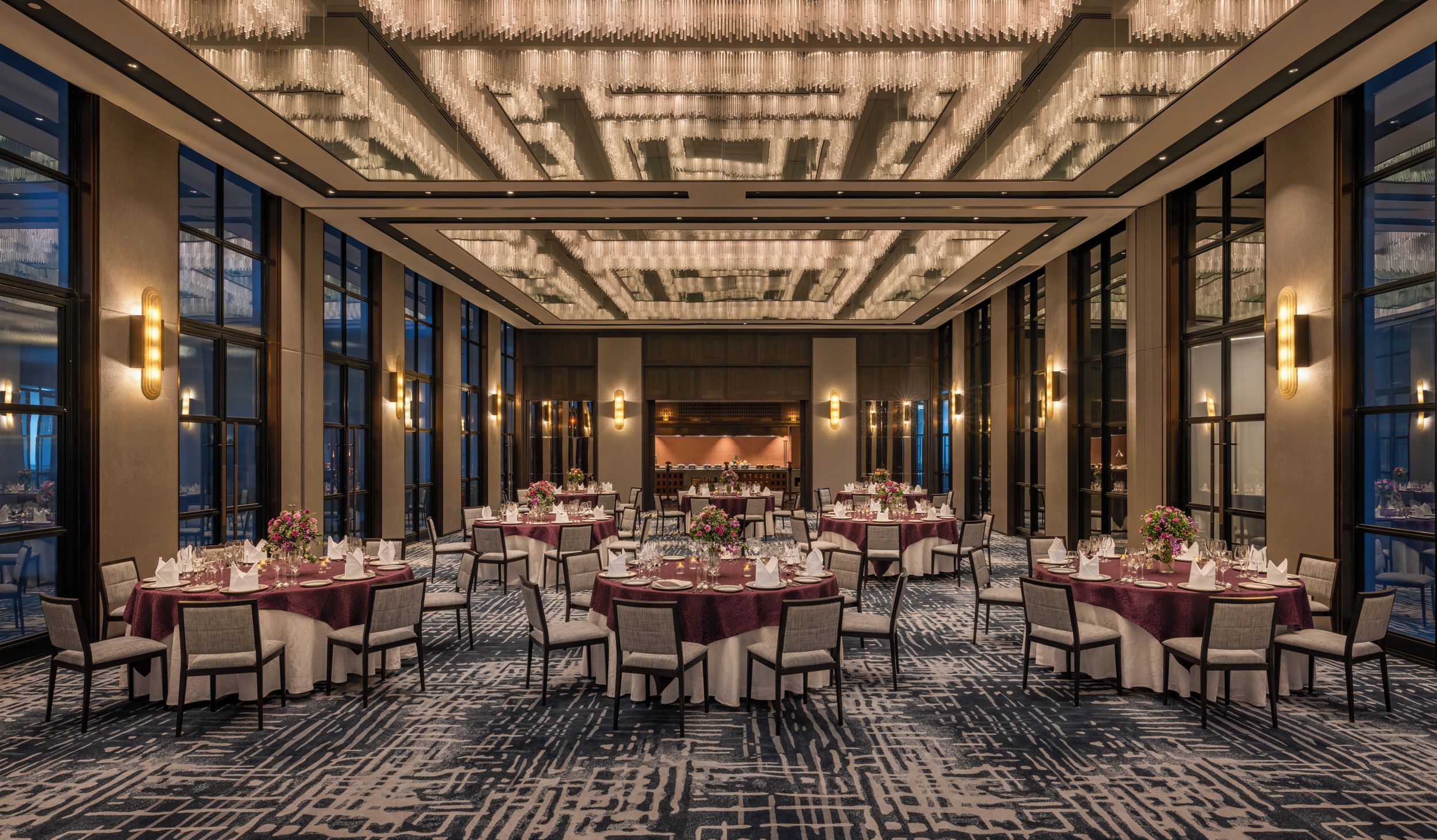 A spacious banquet hall with multiple round tables, each set with chairs and table settings.