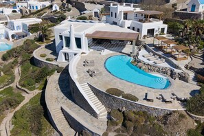 An aerial view of a resort with a large swimming pool, white buildings, and a stone pathway. - Villa Talia with SPA and Pool - My Rental Homes (Mykonos)