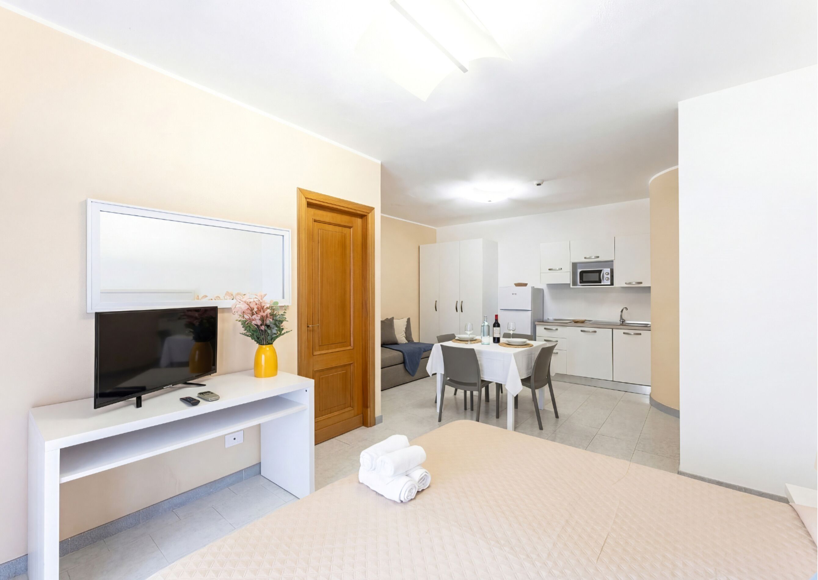 Une chambre d’hôtel moderne équipée d’un lit, d’un bureau avec télévision, d’un coin repas et d’une kitchenette.