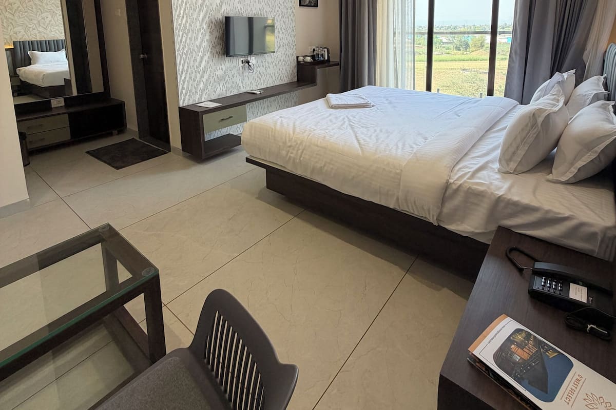 Una habitación de hotel moderna con cama, escritorio, silla, televisor y ventilador de techo.