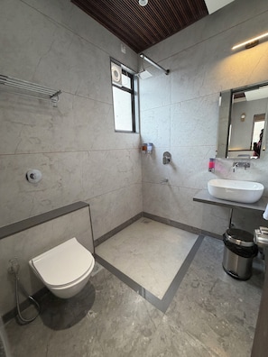 A modern bathroom with a toilet, shower, sink, and mirror.