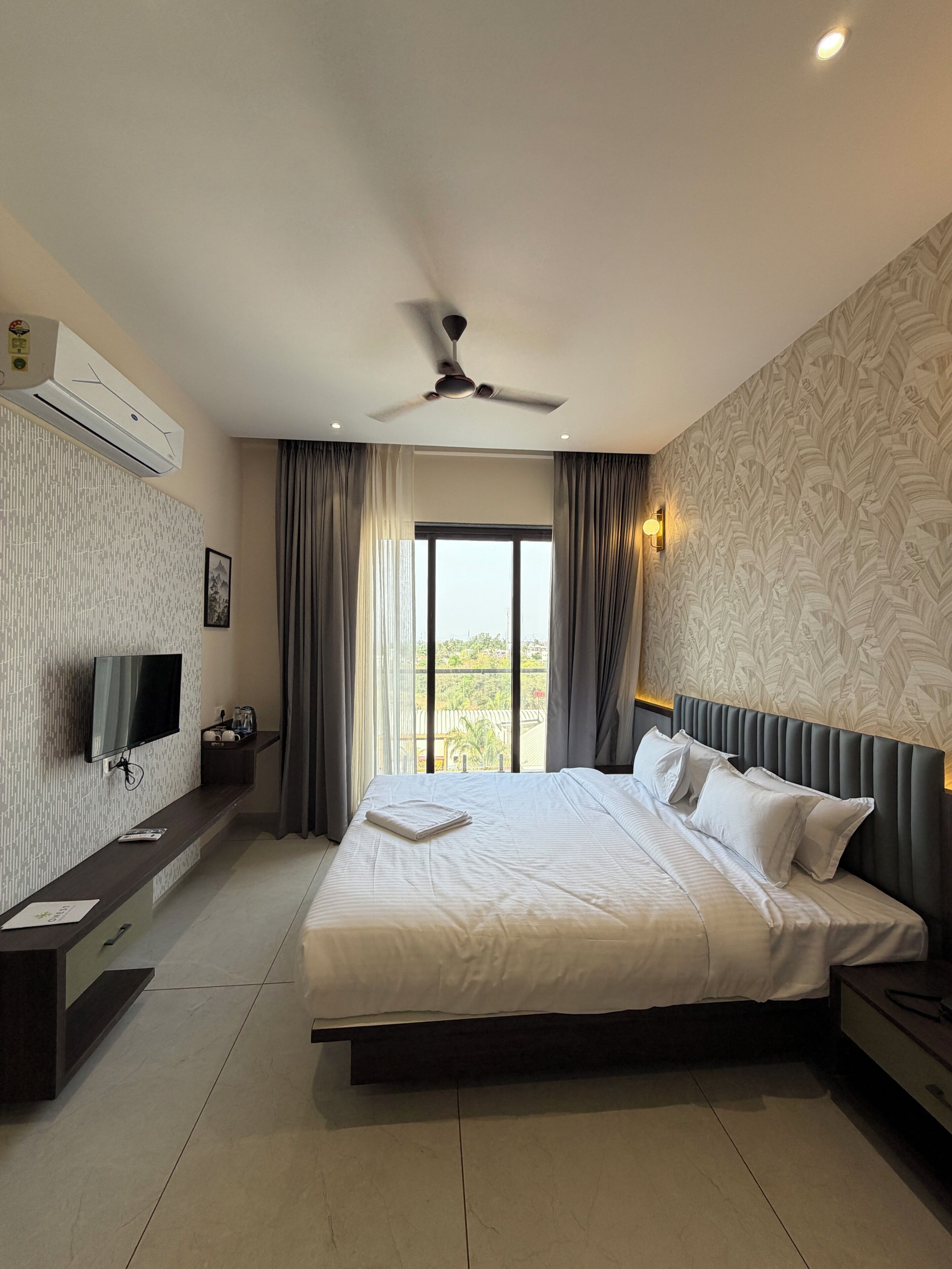 Ein Hotelzimmer mit Bett, Fernseher, Deckenventilator und Blick ins Freie.