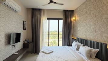 Ein Hotelzimmer mit Bett, Fernseher, Deckenventilator und Blick ins Freie.