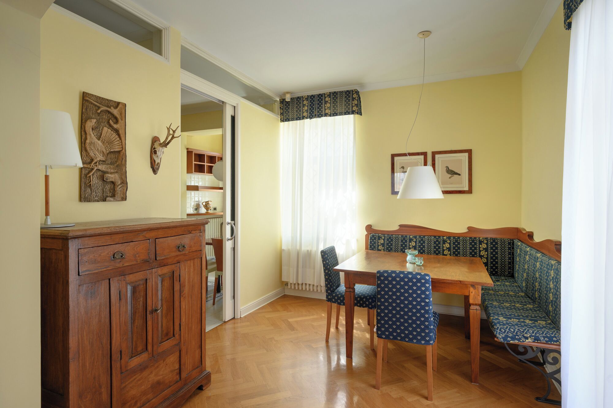 A dining area with a wooden table, chairs, a bench, and a cabinet.