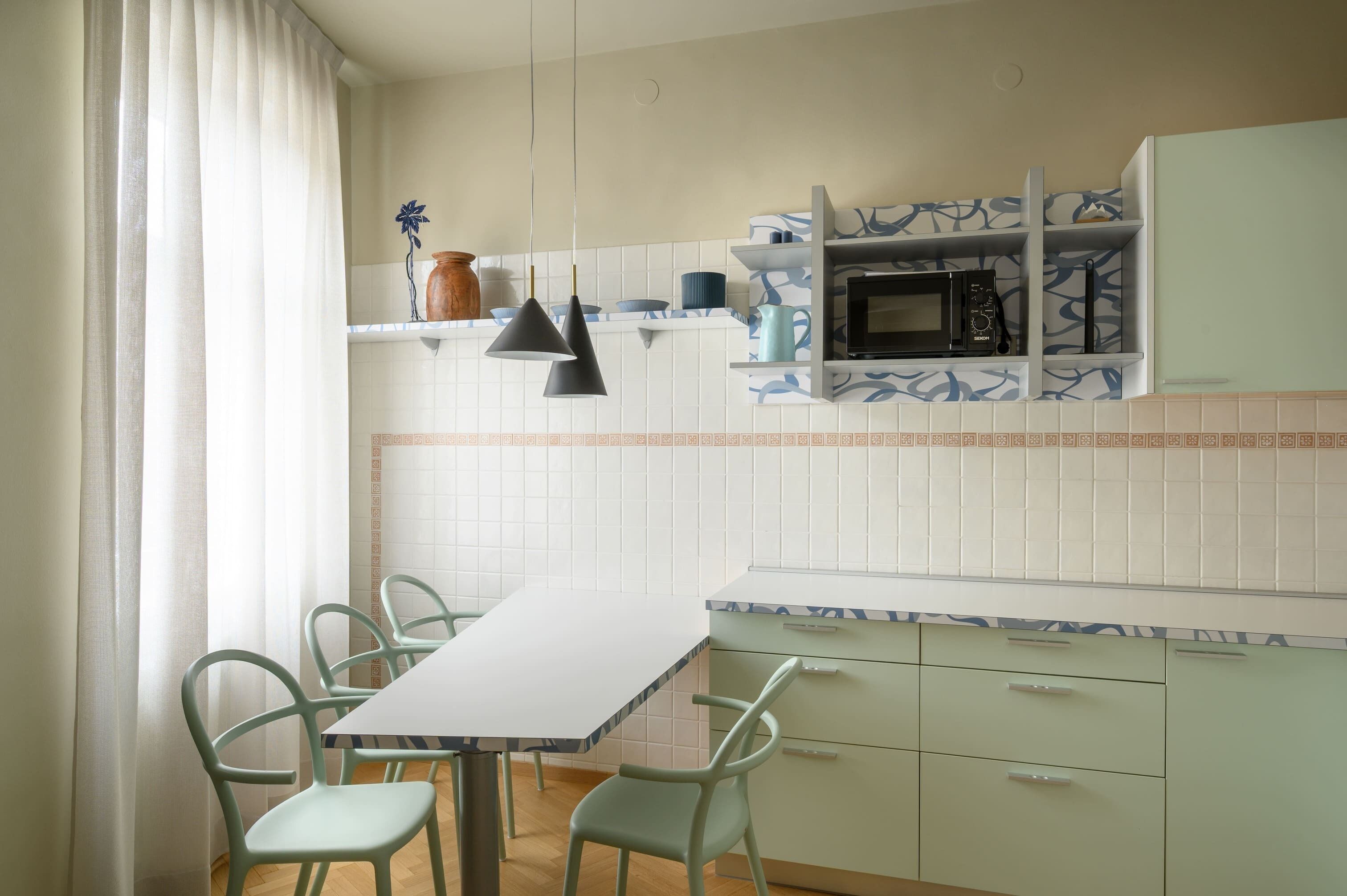Een keuken met een witte tafel en stoelen, een magnetron en planken met servies.