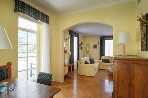 A living room with a wooden table, two sofas, a lamp, and a large window. - Franz Apartments (Ilirska Bistrica)