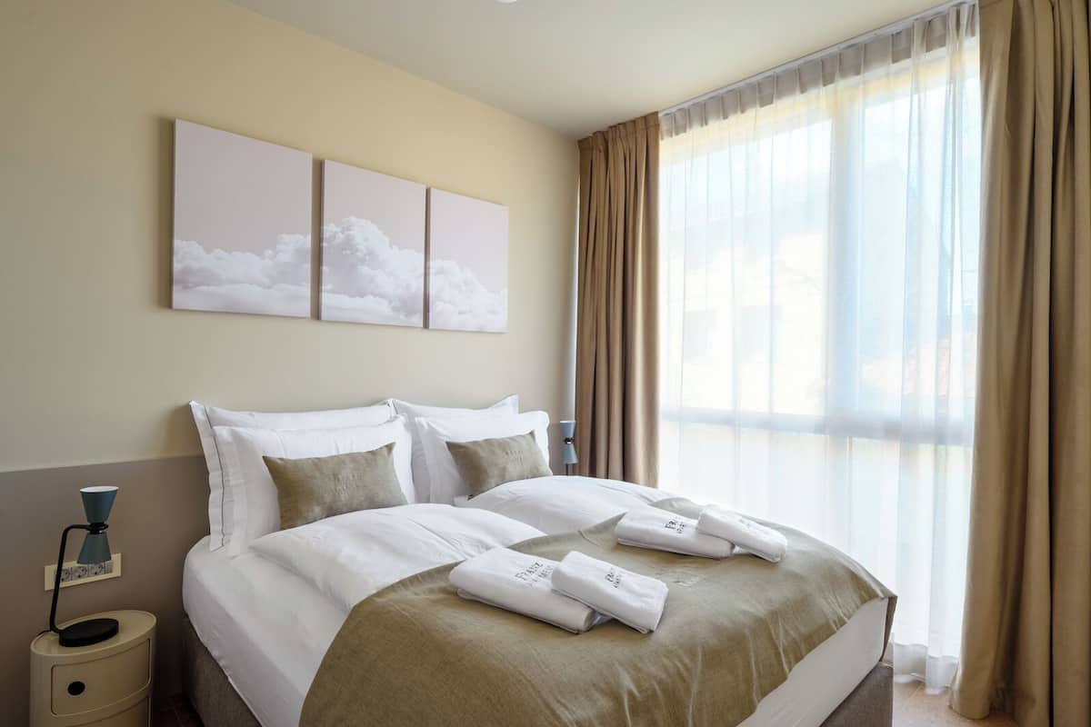 Una habitación de hotel con una cama grande, paredes color beige y una ventana con cortinas.