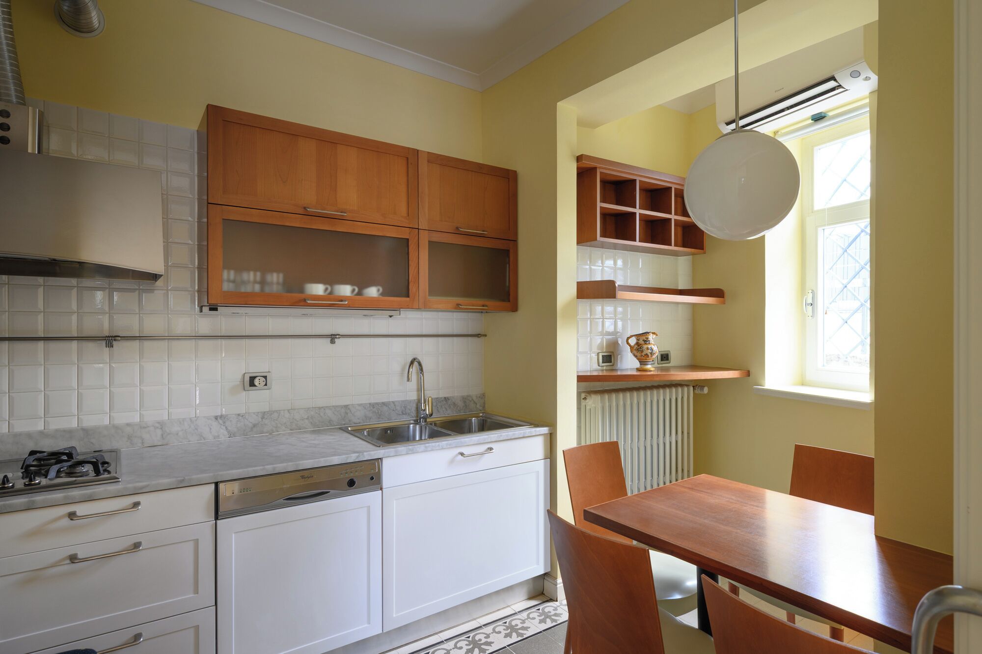 A kitchen with white cabinets, a dishwasher, a sink, and a dining table with chairs.
