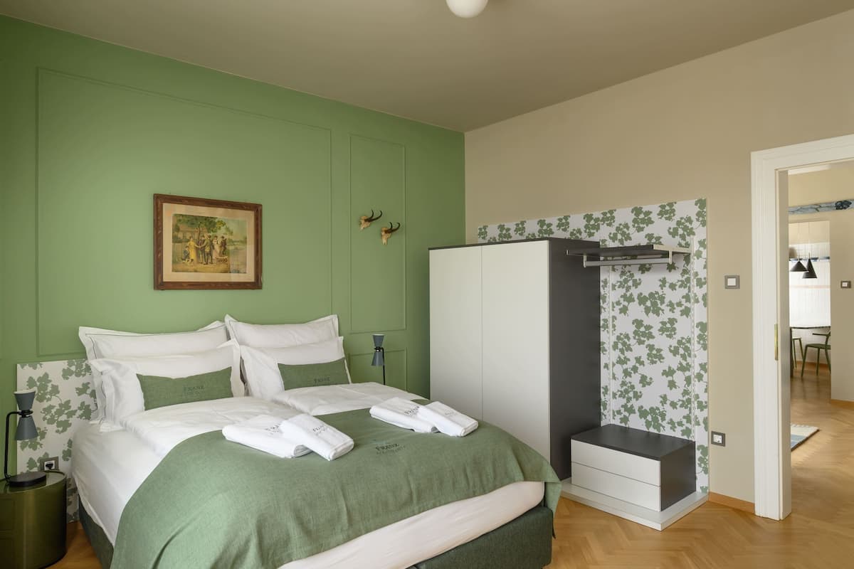 Un dormitorio ordenado con cama, mesitas de noche, un armario y un cuadro en la pared.