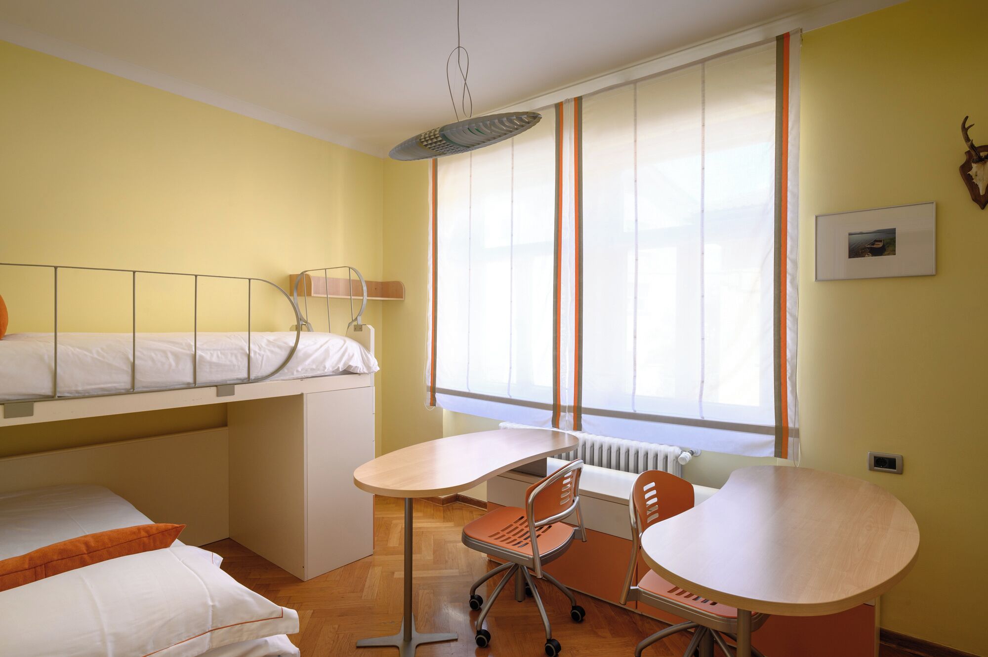 Een kleine kamer met een stapelbed, een tafeltje en een stoel.