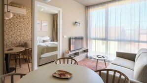 A modern hotel room with a bed, a TV, a dining area, and a sofa. - Franz Apartments  (Ilirska Bistrica)