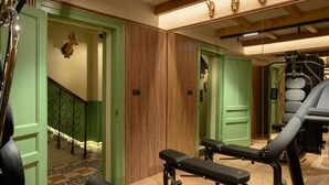 Un gimnasio con equipo de ejercicio, una pared de madera y una escalera con puertas verdes.