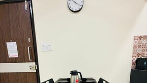 Ein Essbereich mit einem Tisch für vier Personen, einer Wanduhr und einer Tür mit einem Schild.