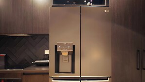Una cocina moderna con un refrigerador de acero inoxidable, dispensador de agua integrado y un salpicadero con motivo de espiga.