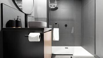 A modern bathroom with a black vanity, a toilet paper holder, and a towel hanging on a rack.