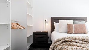 Un dormitorio con cama, mesita de noche y armario.