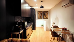 Una cocina moderna con armarios oscuros, encimera negra y una zona de comedor con mesa de vidrio y sillas marrones.