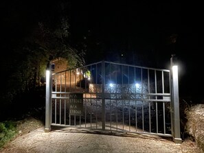 Une grille en métal avec une pancarte, un chemin pavé et un bâtiment en arrière-plan.