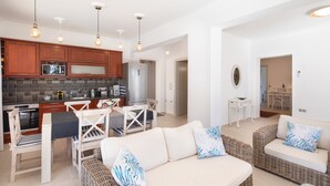 A modern kitchen with wooden cabinets, a microwave, and a dining area with a table and chairs. - Holiday Home 'Modern Single-story Villa' with Wi-Fi (Mparmpati)