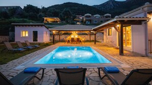 A swimming pool with lounge chairs, a covered patio, and a mountainous backdrop. - Holiday Home 'Modern Single-story Villa' with Wi-Fi (Mparmpati)