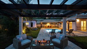 A covered outdoor patio with wicker furniture, a pool, and a stone pathway. - Holiday Home 'Modern Single-story Villa' with Wi-Fi (Mparmpati)