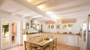 Una cocina moderna con armarios blancos, una mesa de comedor de madera y vistas al patio exterior.