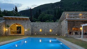 Una piscina con un muro de piedra y un edificio de piedra con chimenea.