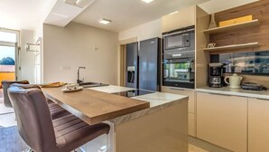 Una cocina moderna con una isla central, electrodomésticos integrados y un comedor con sillas.