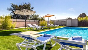 Una piscina con sillones de descanso y sombrillas.