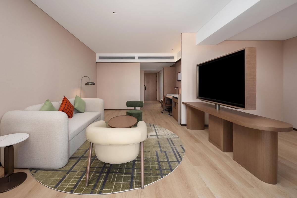 Una sala de estar moderna con un sofá, un sillón, un televisor y una mesita.