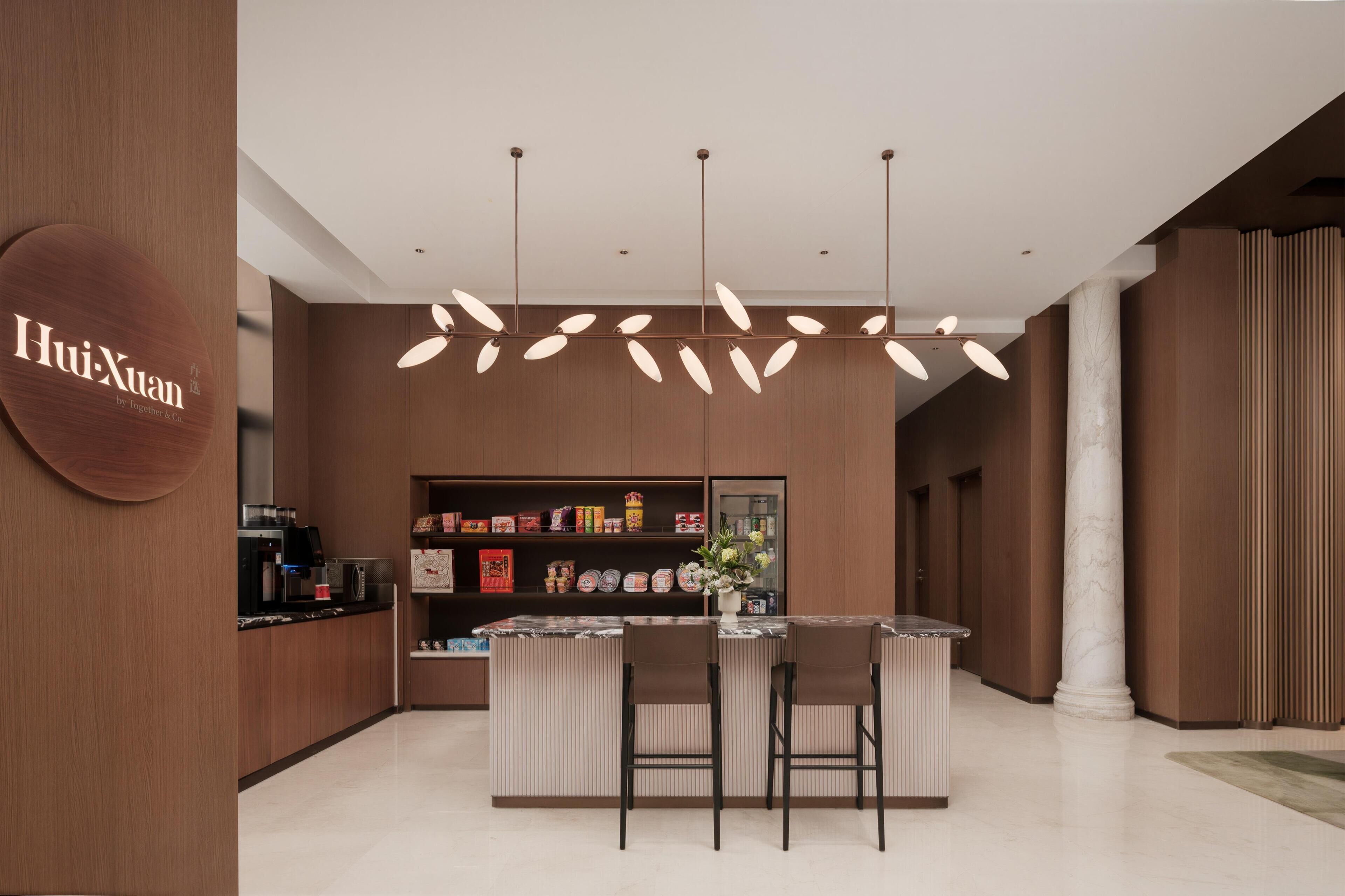 A modern kitchen with a central island, pendant lighting, and a visible sign reading 'HuiXuan'.