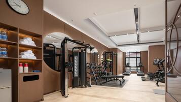 A gym with exercise equipment, a clock, and a water dispenser.