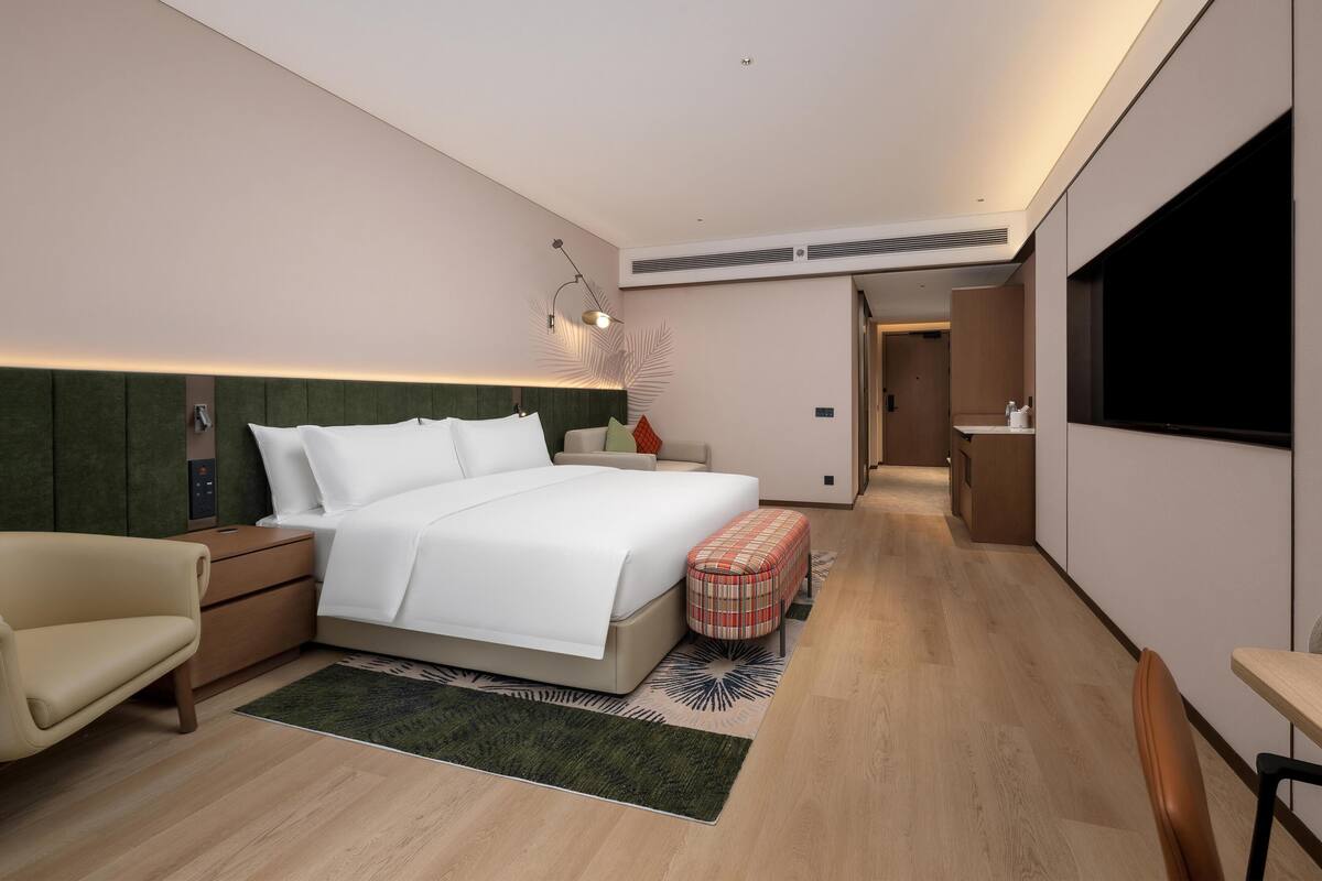 Una habitación de hotel moderna con una cama grande, un escritorio, una silla y una televisión.
