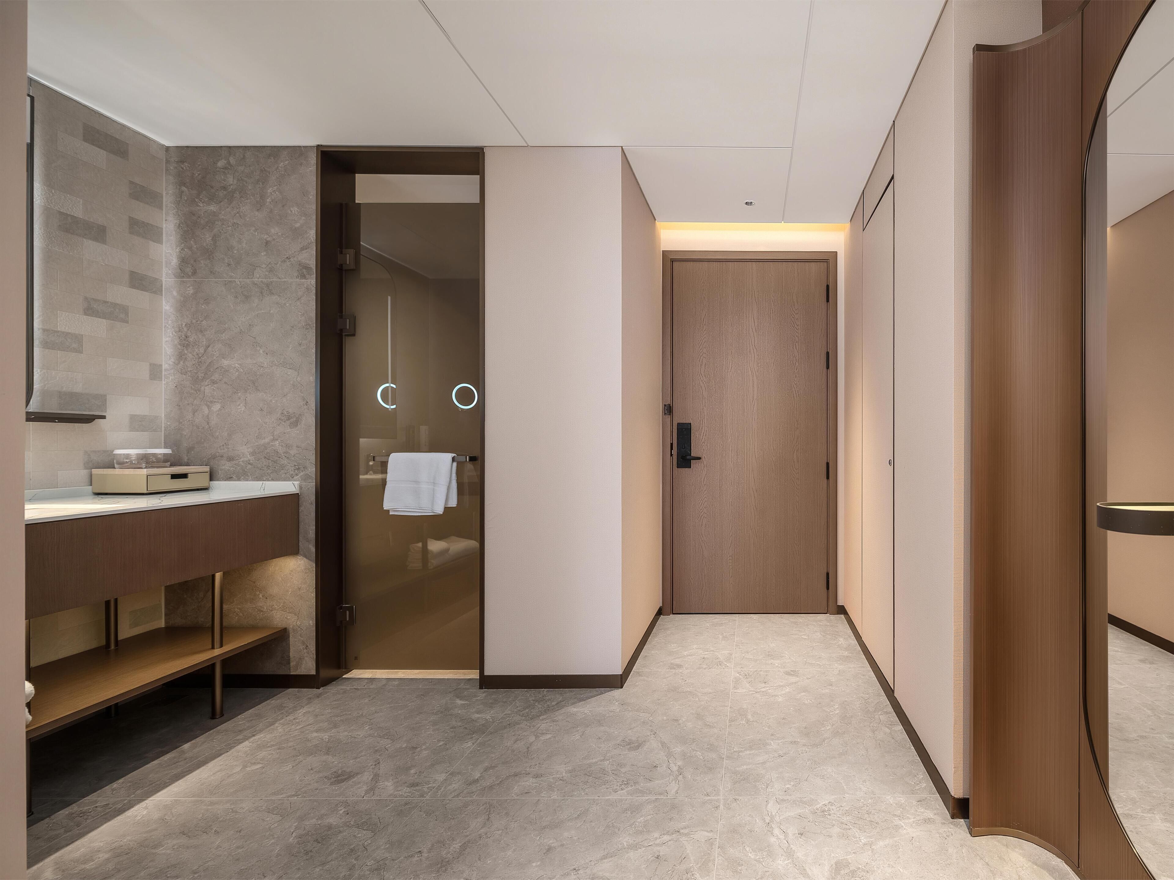 A modern bathroom with a vanity, towel rack, and a door leading to a shower area.