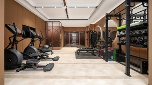 Un gimnasio con cintas de correr, elípticas, prensa de banca y racks de pesas.