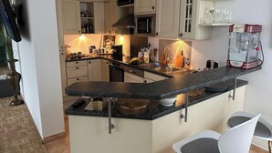 A modern kitchen with a central island, white cabinetry, and a built-in oven. - Room-in the Heart of the City of Salzbur (Salzburg)