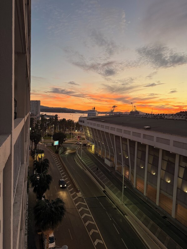 A view of a coastal cityscape at sunset with a bridge and road infrastructure. - Upscale 4-bedroom apartment with large balcony (Toulon)
