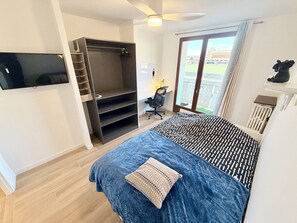 A bedroom with a bed, a wardrobe, a desk, a chair, a television, and a sliding glass door to the outside. - Upscale 4-bedroom apartment with large balcony (Toulon)