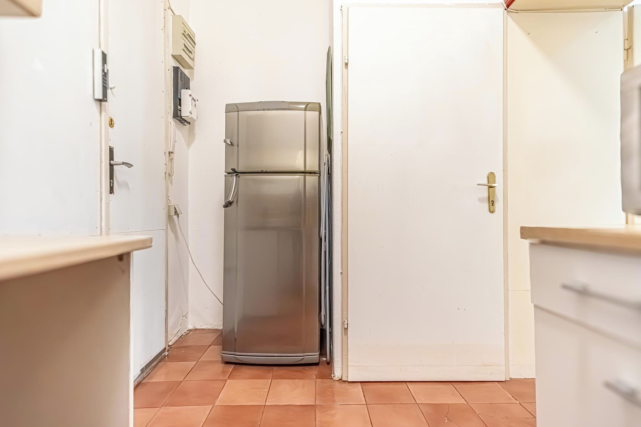 Une cuisine de taille réduite, équipée d’un réfrigérateur, d’un évier et d’un plan de travail.